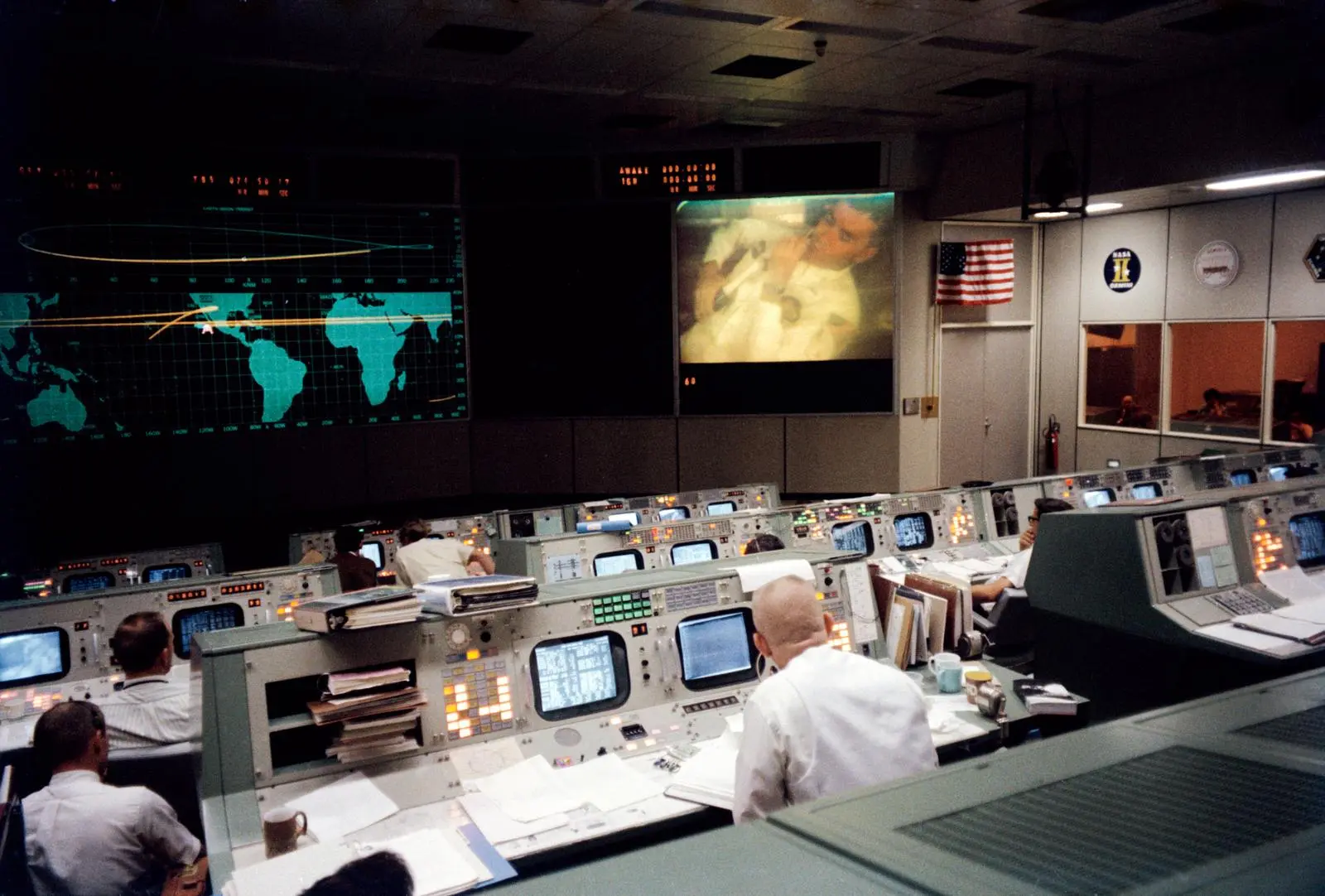 Gene Kranz (back to camera) watches Fred Haise on the big screen during the TV broadcast that ended nine minutes before the explosion, 13 April 1970 (S70-35139)