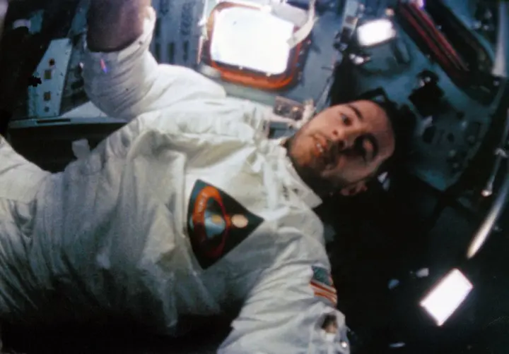 Bill Anders at work inside the command module, from the onboard 16mm movie camera (S68-56532)