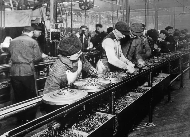 Workers on Ford’s first moving assembly line build flywheel magnetos at Highland Park, 1913.