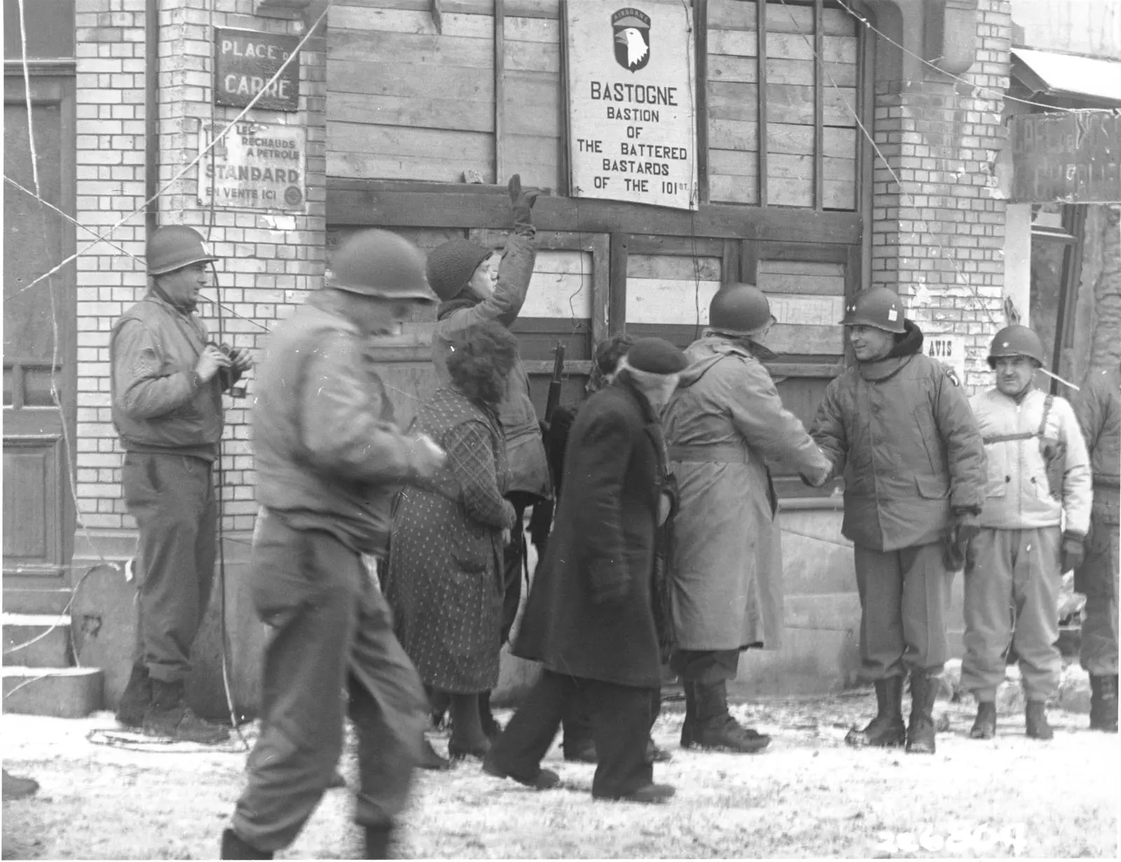 Generals of the 101st review the division in Bastogne beneath the sign its men put up: Bastion of the Battered Bastards of the 101st, January 1945