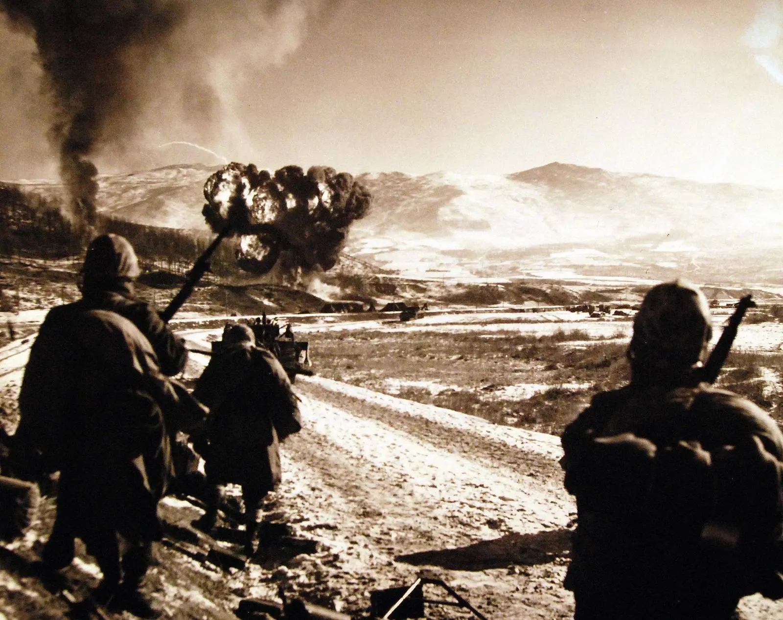 A Marine Corsair pulls up through the smoke after a napalm strike as 7th Marines watch from the road south of Hagaru-ri, 6 December 1950 (A-5464)
