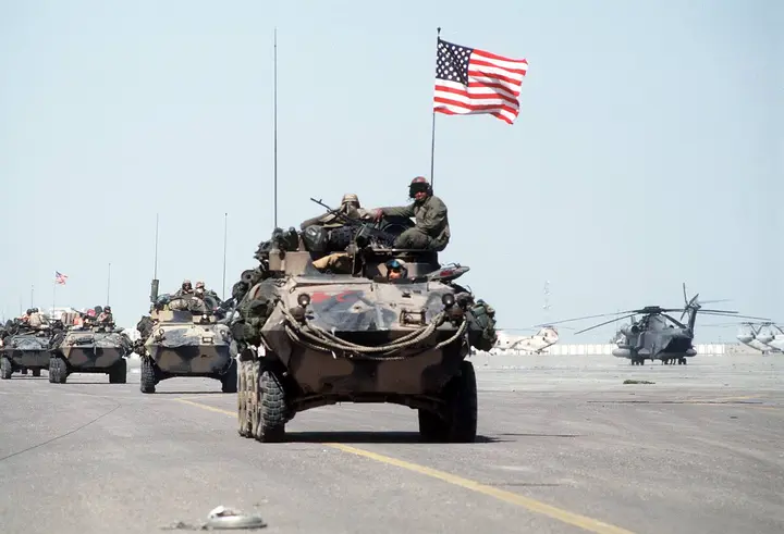 Marines roll into Kuwait International Airport in light armored vehicles, flag flying, after the Iraqi retreat, 27 February 1991.