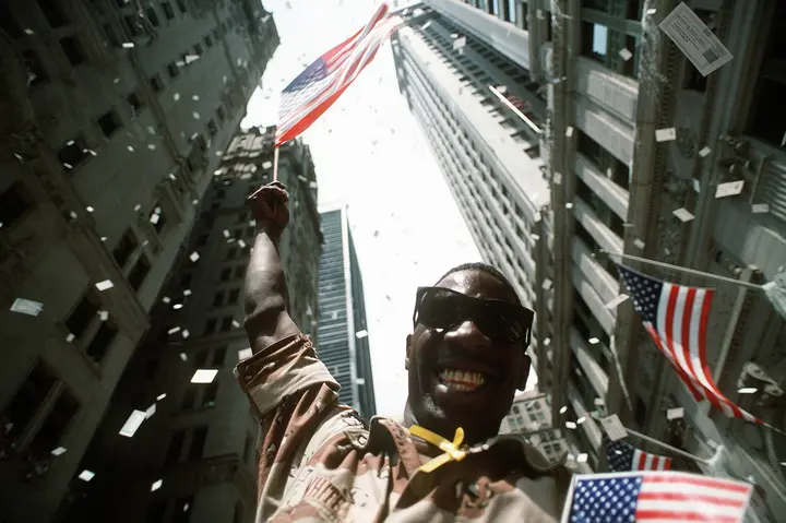 Pfc. White of the U.S. Army waves the flag under falling ticker tape at New York’s Welcome Home parade for the troops of Desert Storm, 10 June 1991.