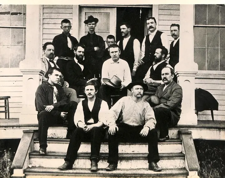 Edison with his Menlo Park team on the laboratory porch, Francis Upton and Charles Batchelor beside him