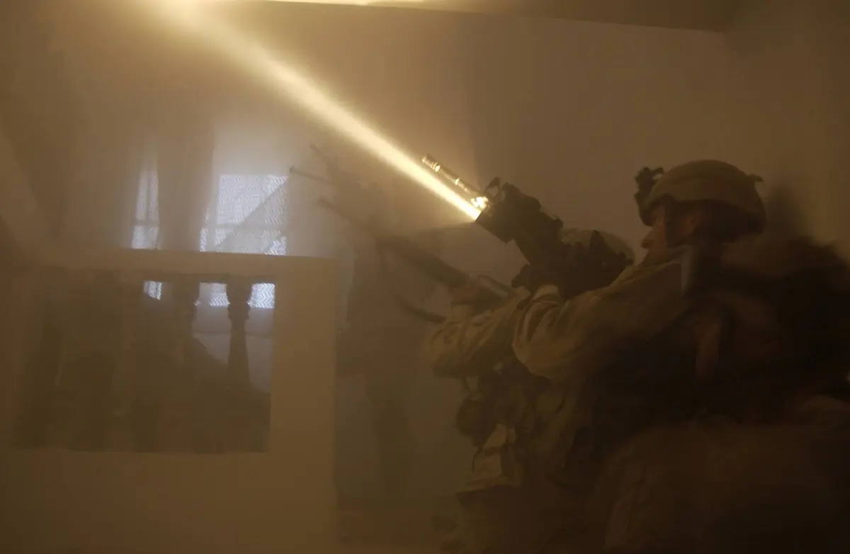 The beam of a rifle-mounted flashlight cuts through the dust as U.S. Army soldiers clear a house in Fallujah, 13 November 2004.