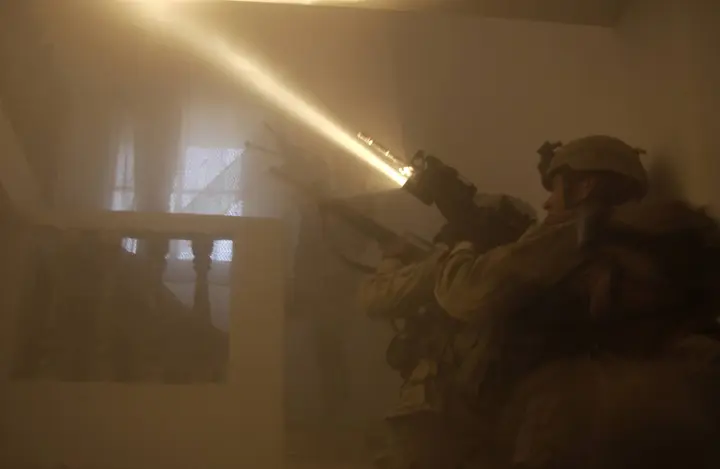 The beam of a rifle-mounted flashlight cuts through the dust as U.S. Army soldiers clear a house in Fallujah, 13 November 2004.