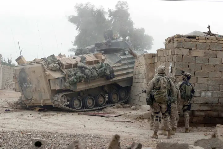 An amphibious assault vehicle smashes through a wall and a locked gate to open a way in for Marines of India Company, 3d Battalion, 1st Marines, 17 November 2004.