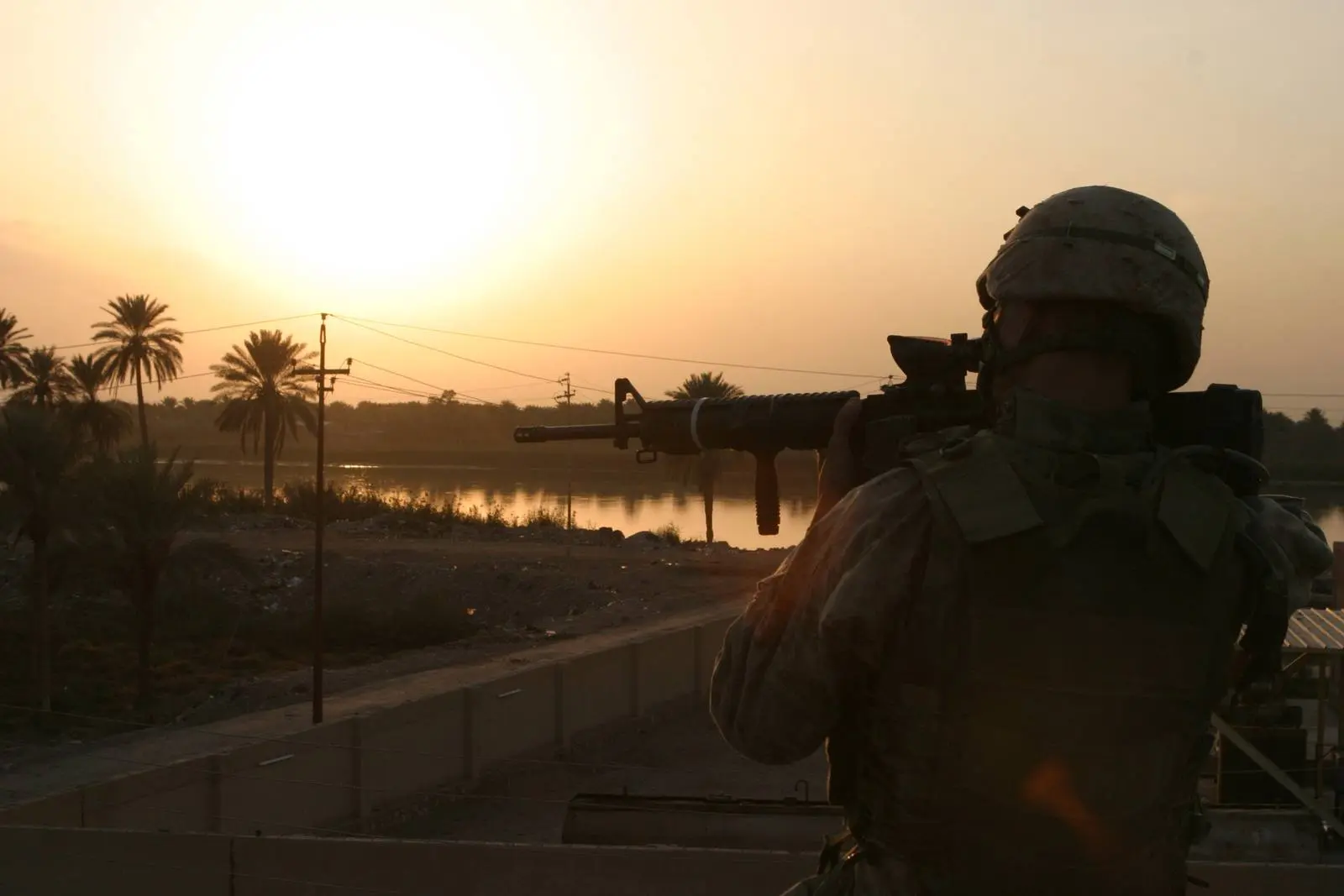 Marines of 3d Battalion, 5th Marines, patrol south toward a palm grove at sunset, clearing every house on the way, 15 November 2004.
