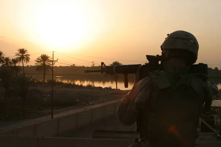Marines of 3d Battalion, 5th Marines, patrol south toward a palm grove at sunset, clearing every house on the way, 15 November 2004.