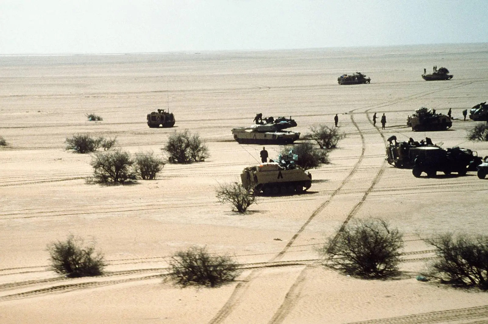 M1A1 Abrams tanks and armored vehicles of the 3rd Armored Division move out across open desert during Operation Desert Storm.