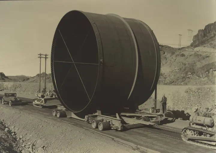 A 30-foot-diameter steel penstock section hauled to the dam on a special trailer, photographed by Ben Glaha, c. 1934