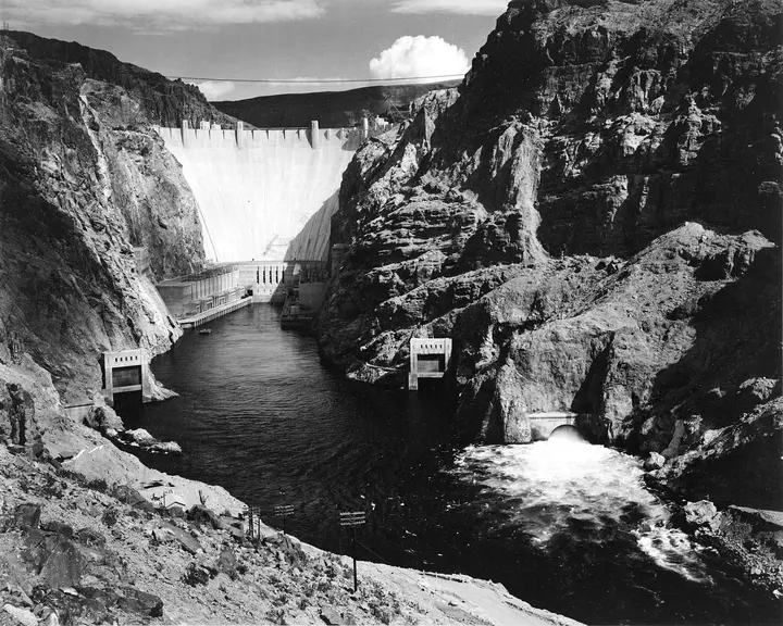 Boulder Dam from downstream, with the canyon-wall outlet works and the Colorado River below, photographed by Ansel Adams, 1941