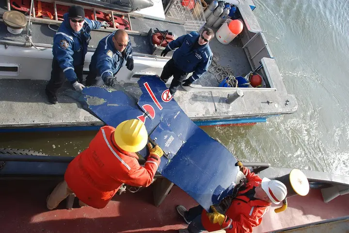 NYPD scuba divers hand up a piece of engine cowling to an Army Corps of Engineers crew during the recovery, 21 January 2009