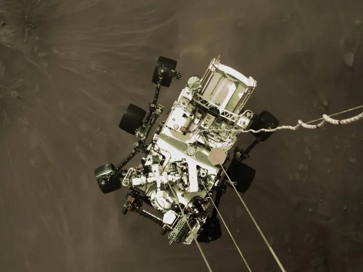 The descent stage lowers Perseverance on nylon cords seconds before touchdown in Jezero Crater, 18 February 2021