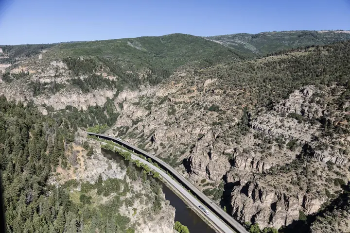 Interstate 70 rides its viaduct along the Colorado River through Glenwood Canyon, Colorado, the final stretch of I-70, opened in 1992. Aerial photograph, 2016.