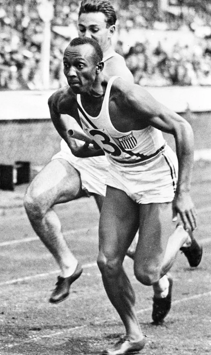 Owens, baton in hand, in the 4×100 metres relay at Berlin, 1936