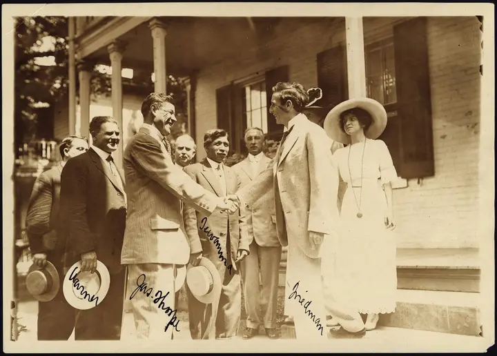 Thorpe shakes hands with Carlisle superintendent Moses Friedman as Pop Warner, left, and Louis Tewanima, center, look on