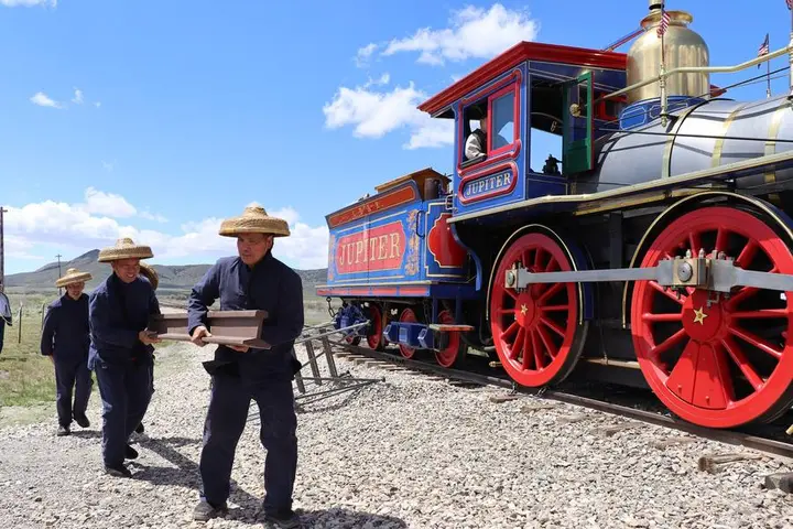 Living-history volunteers carry the last rail past the Jupiter replica at Promontory Summit