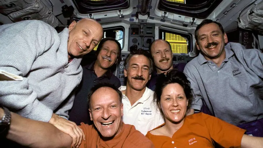 The STS-61 crew on Endeavour’s flight deck with Hubble berthed in the payload bay, December 1993 (STS061-05-031).