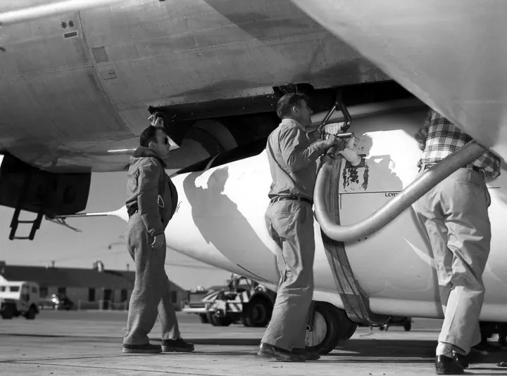 Technicians service an X-1 mated to its B-29 mothership; the shackles held it until the drop.