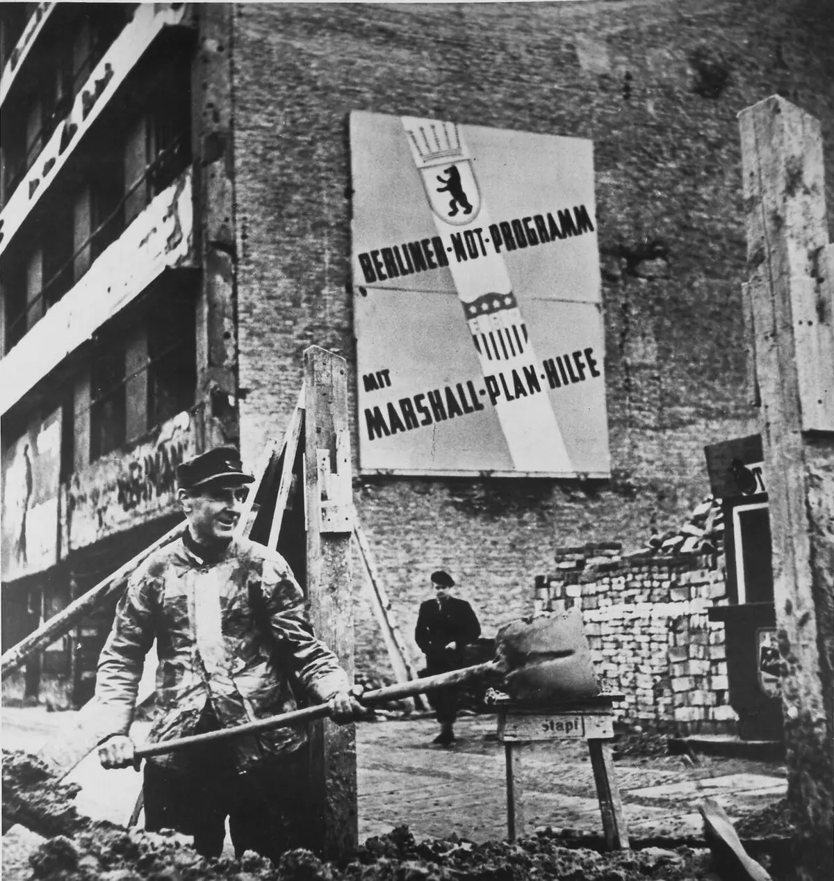 A worker clears rubble in West Berlin beneath a sign for the city’s emergency program “with Marshall Plan aid.” A year before the plan ended, West Germany had passed its prewar industrial output.