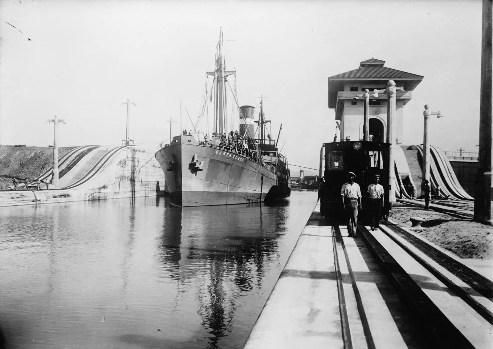 An electric towing locomotive guides the S.S. Santa Clara into the lower west chamber of the Miraflores Locks in the canal's early years