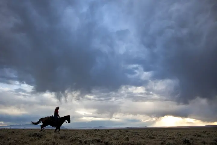 A modern rider retraces the Pony Express National Historic Trail across the Wyoming sagebrush under a storm sky, September 2010.