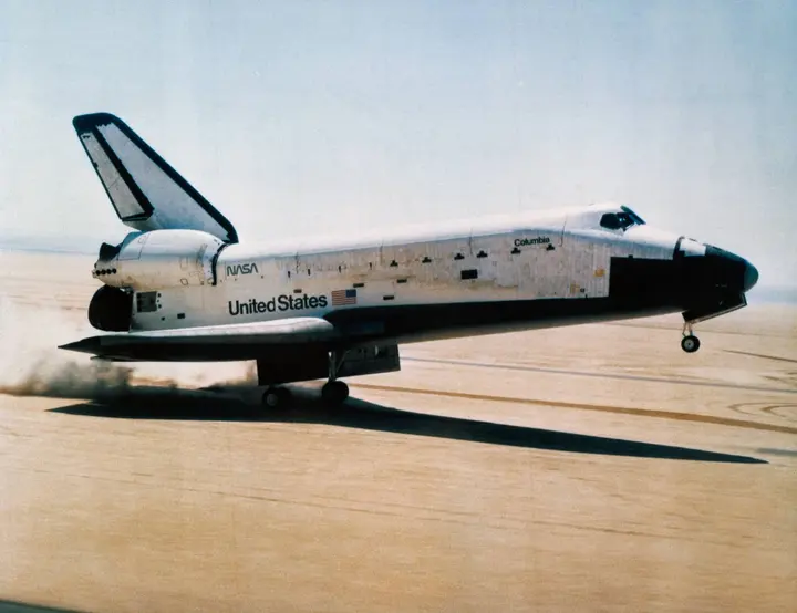 Columbia’s main wheels touch down on Rogers Dry Lake at Edwards Air Force Base, 14 April 1981, the first NASA spaceflight to end on a runway (S81-30746)