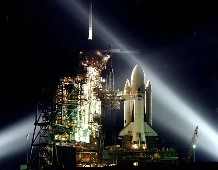 Searchlights frame Columbia on Pad 39A in a timed night exposure weeks before the first launch, March 1981 (KSC-81PC-0136)