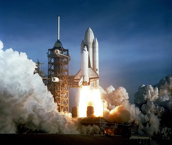 Columbia rises from Pad 39A just after 7 a.m. on 12 April 1981, its external tank still painted white, the first time a crew rode a spacecraft on its maiden launch (KSC-81PC-0382)