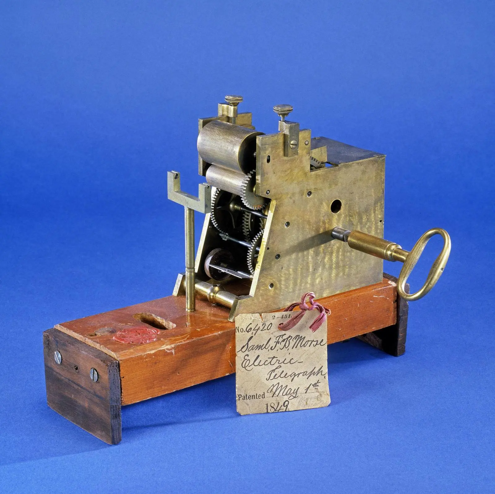 A Morse electric telegraph register, tagged “Patented May 1st 1849.” Its stylus embossed dots and dashes on a moving paper tape.