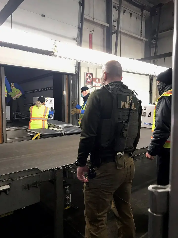 A Deputy U.S. Marshal watches over a vaccine shipment at a loading dock during the first deliveries, 14 December 2020.