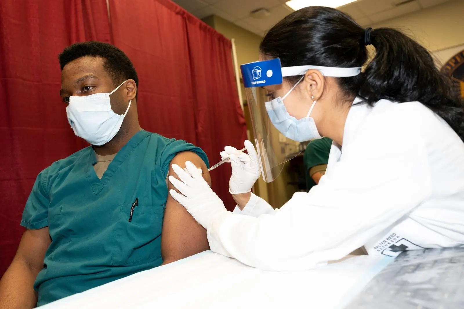 Army Capt. Isaiah Horton, a doctor at Walter Reed National Military Medical Center, gets one of the military’s first COVID-19 shots, 14 December 2020.