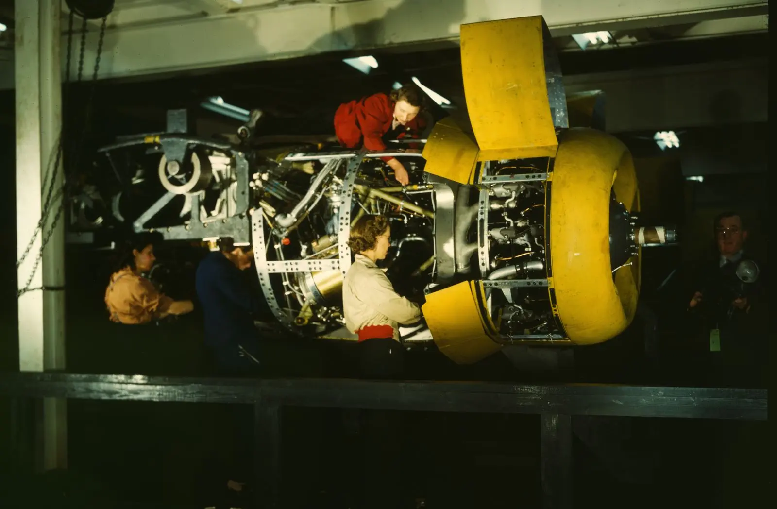 Installing one of the four engines on a plane at Willow Run, photographed in color by Howard Hollem